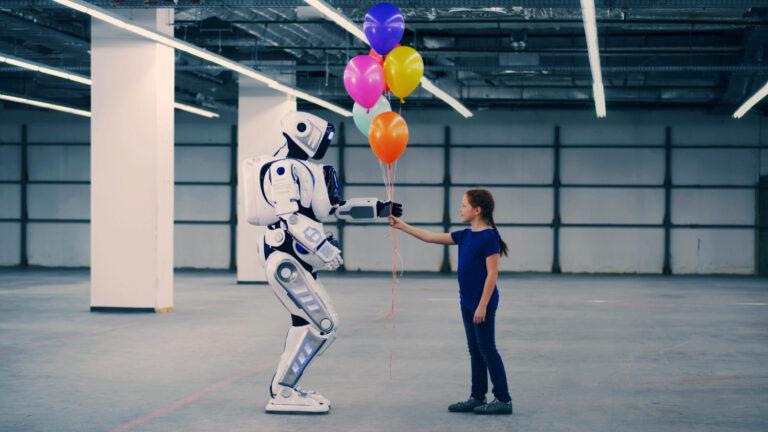 Flicka ger ballonger till robot. Foto.